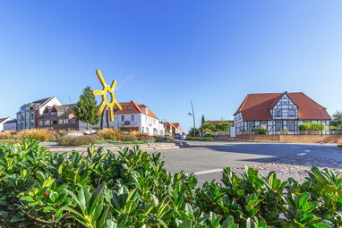 Blick auf eine sonnige Kreuzung in Grömitz mit markanter gelber Skulptur und typisch norddeutscher Bebauung.